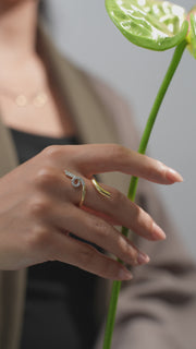 Model wearing 18k gold ring and holding flower, close up of the jewelry